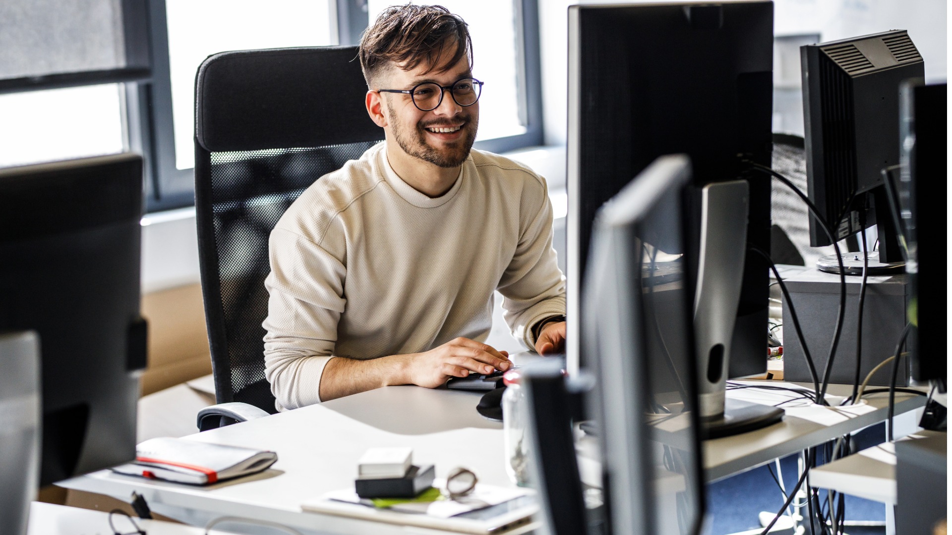 A smiling developer surrounded by monitors